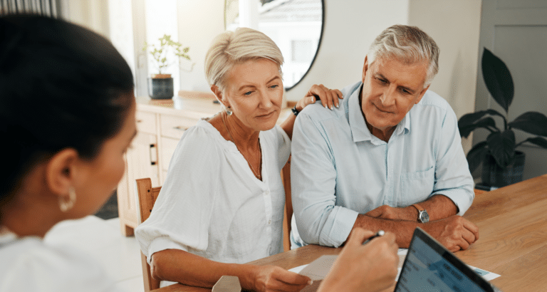 An elderly couple reviewing documents with a financial professional.