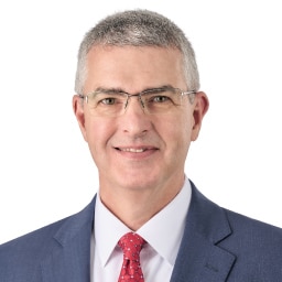 A headshot of associate Brian Campbell. He has short gray hair and is wearing rimless eyeglasses and a blue suit.