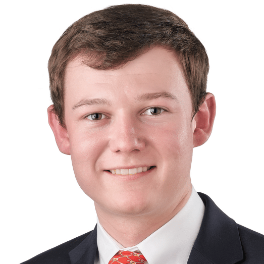 A headshot of associate Benjamin Anderson. He has short brown hair and he is wearing a black suit.