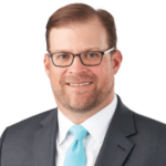 A headshot of associate Brian Taylor, CTFA. He has short brown hair and he is wearing a gray suit.