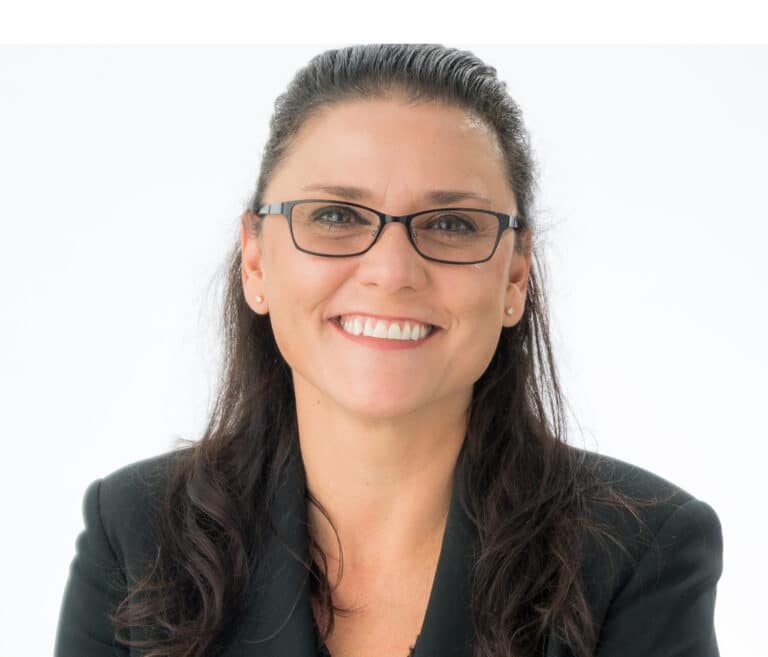 A headshot of associate Donna Cunningham, a woman with long black hair and rectangular glasses, smiling at the camera.