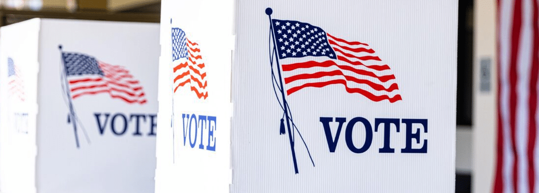 White cardboard privacy partitions depicting an American flag and a "VOTE" slogan, used by voters during elections in the United States of America.