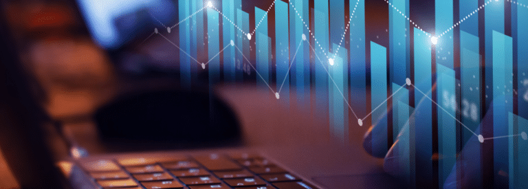An image depicting line and bar charts in front of a laptop keyboard.
