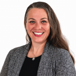 A headshot of associate Sarah Ryder. She has long brown hair and she is wearing a gray cardigan sweater.