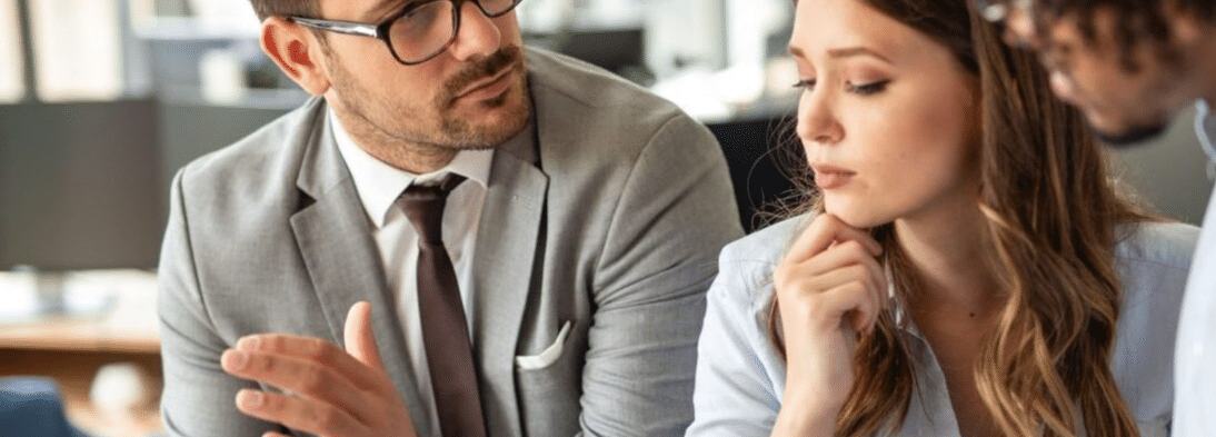 A business man and a business woman, in business formalwear. They are having a discussion.