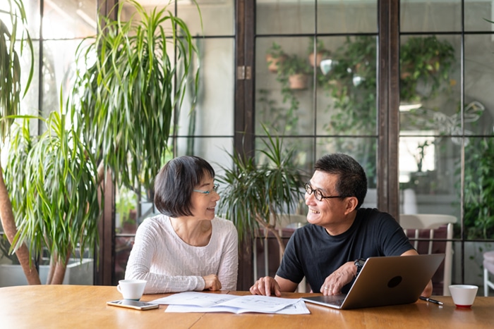 Couple sitting at a table with a laptop.