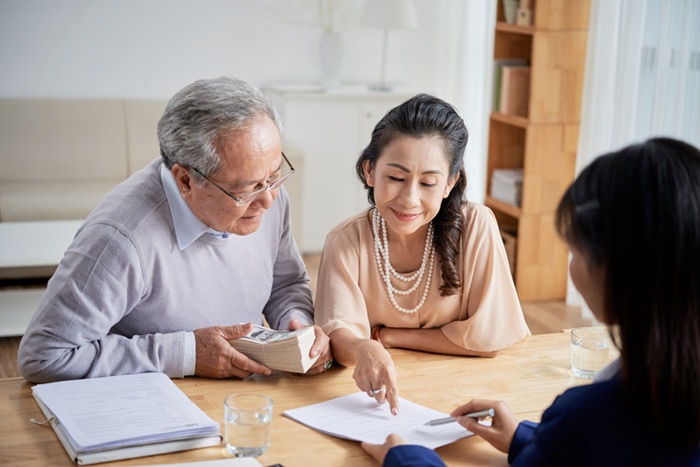 An older couple filling out a form with a banker.