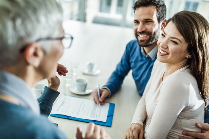 A couple meeting with a banker and smiling.