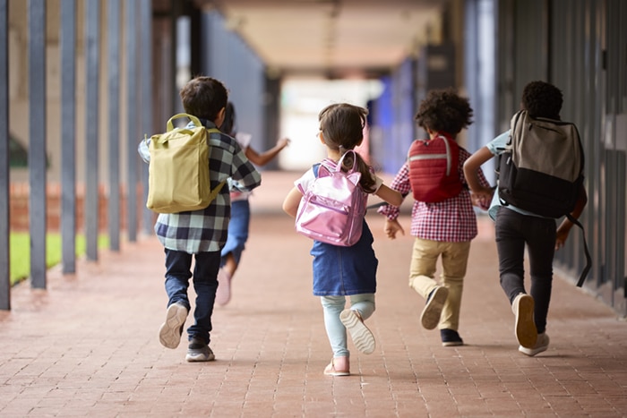 Schoolchildren running with backpacks.