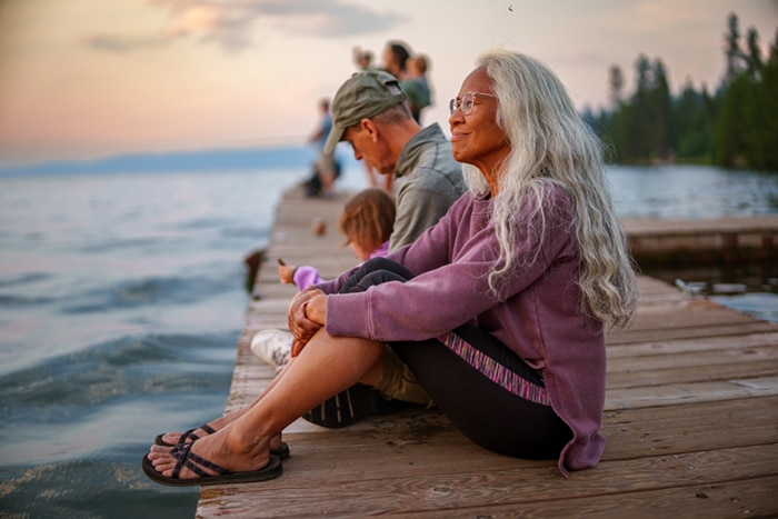 An older woman sitting on a dock.