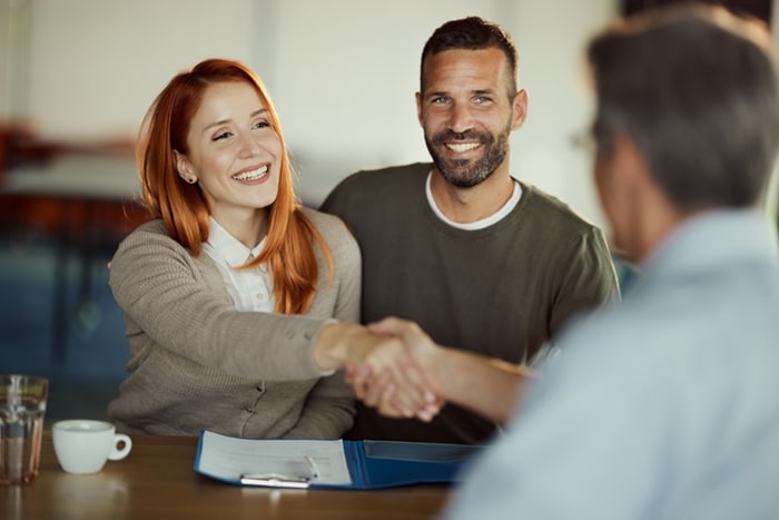 A couple shaking hands with a banker.