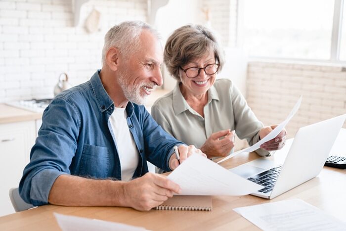 A couple with papers in front of their laptop.