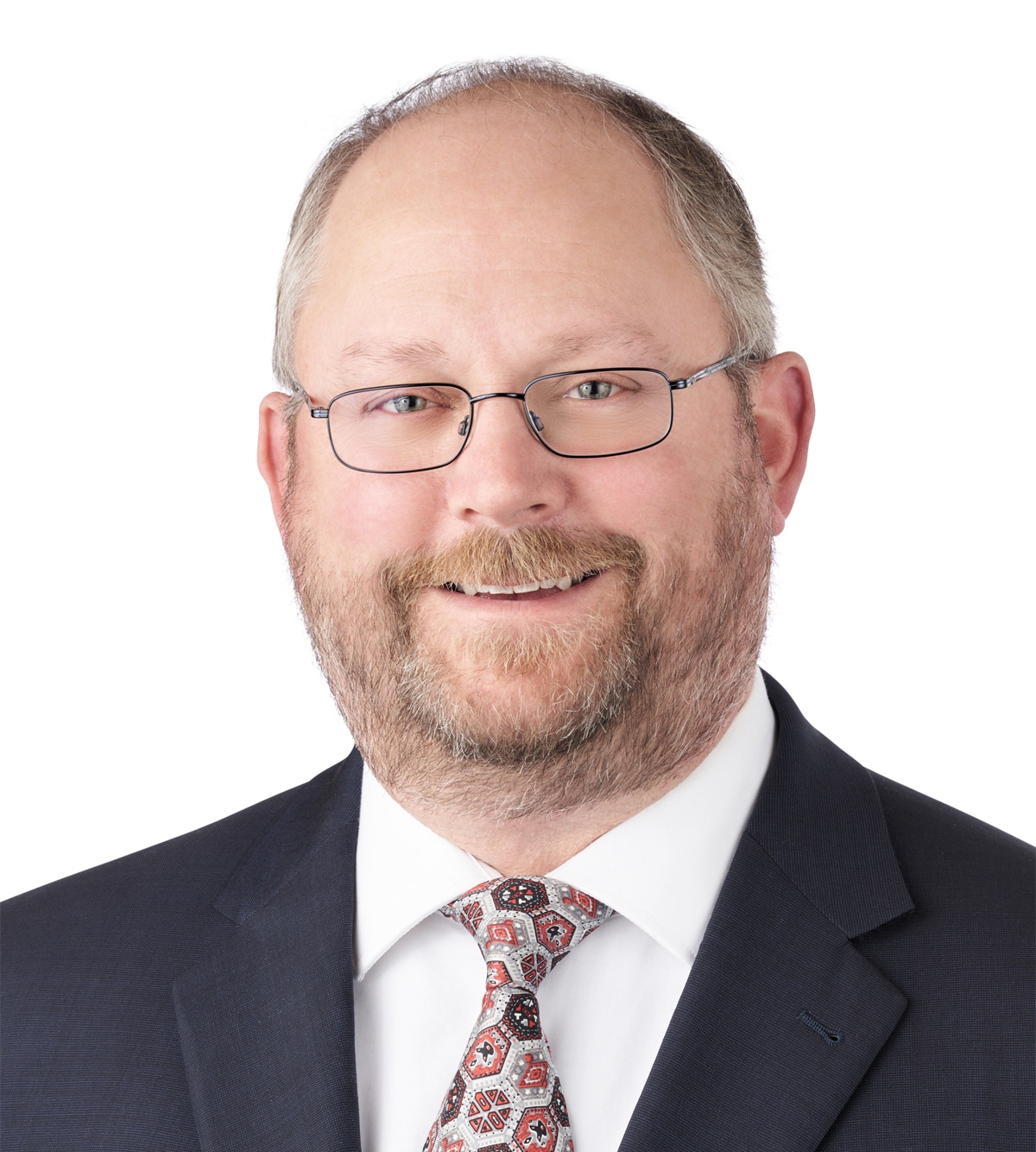 A headshot of associate Jesse Ashcroft. He is wearing wireframe glasses and a dark suit.