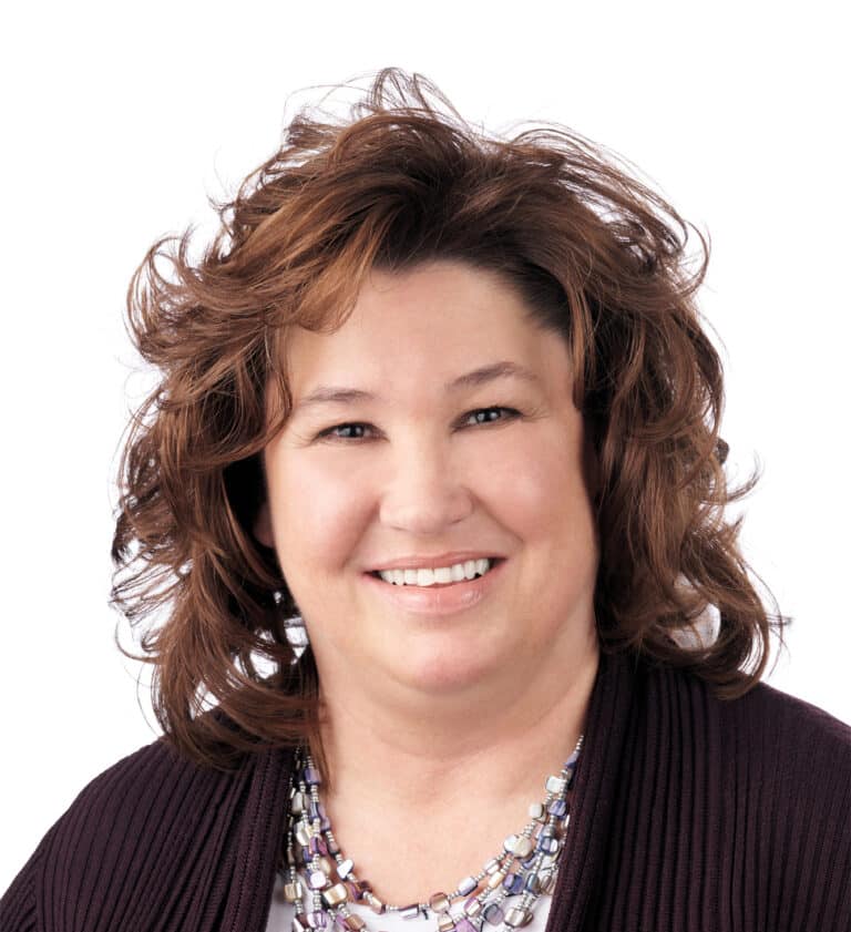 A headshot of associate Kelly Groscost, CTFA. She has wavy brown hair and is wearing a brown cardigan sweater.