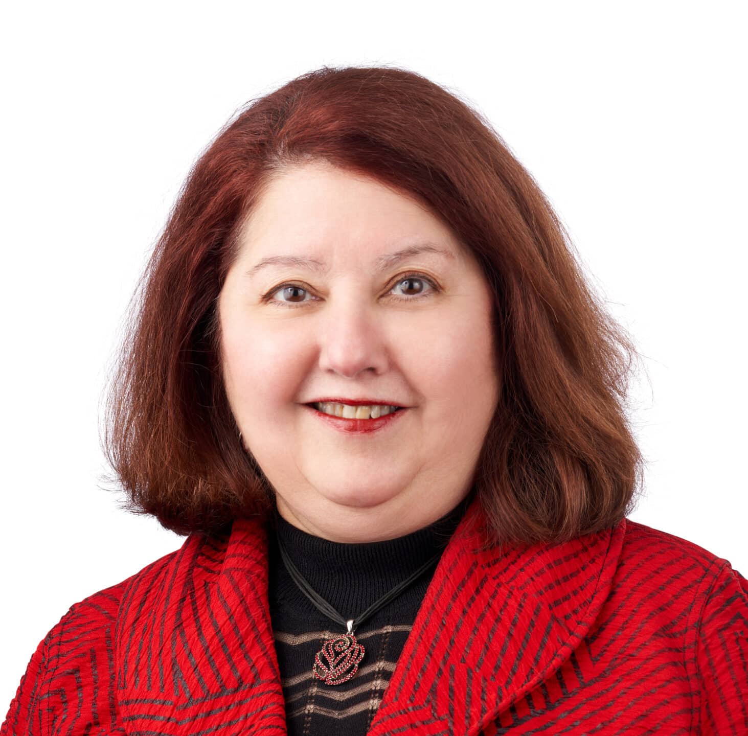 A headshot of associate Mary Lisa O'Neill. She has shoulder length red hair and is wearing a red, patterned blazer.