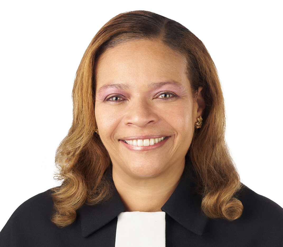 A professional headshot of Seane Baylor. She is wearing a black and white shirt.