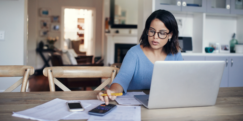 A woman using a laptop and a calculator.